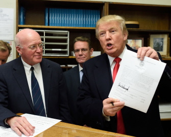 Donald Trump muestra su inscripción para las elecciones primarias en New Hampshire, ante el secretario de dicho estado, William Gardner (i) 