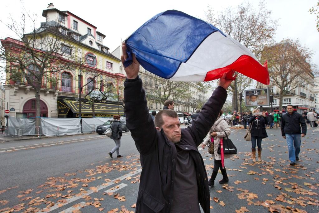 Un hombre extiende la bandera francesa frente a la sala de conciertos Bataclán. 