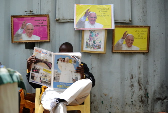 Un keniano lee un ejemplar del diario "Catholic Mirror" (Espejo Católico) junto a fotos del papa en la Basílica de la Sagrada Familia en Nairobi, Keni