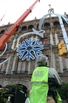 Trabajadores del gobierno capitalino montan la decoración navideña que lucirán edificios contiguos al Zócalo.