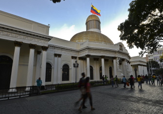 Un grupo de personas camina junto al edificio de la Asamblea Nacional, en Caracas, un día después del triunfo opositor