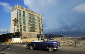 Un viejo auto de fabricación estadunidense pasa junto a la embajada de Estados Unidos, hoy en La Habana