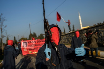 Un militante izquierdista enmascarado muestra su AK-47 durante el funeral de dos mujeres militantes muertas por la policía en Estambul