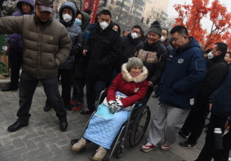 Una simpatizante de Pu Zhiqiang, rodeada de agentes policiales chinos de paisano, durante el juicio en Pekín