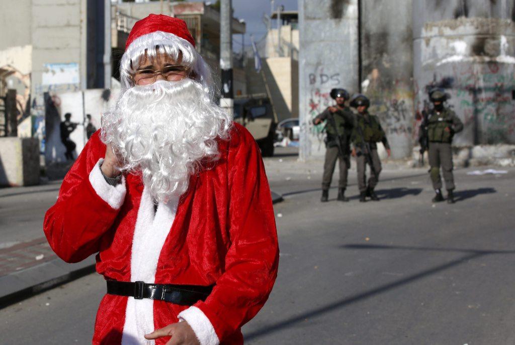 Un palestino disfrazado de Papá Noel se manifiesta contra Israel frente al controvertido muro de separación construido en Belén, Palestina. 