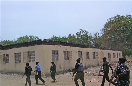 Fuerzas de seguridad nigerianas caminan junto a una escuela secundaria estatal incendiada en Chibok, donde Boko Haram raptó a 200 jóvenes