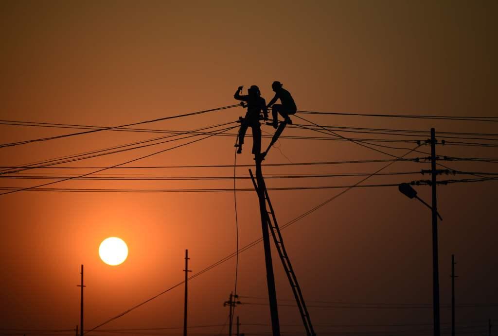 Un grupo de trabajadores ajustan los cables de electricidad establecidos temporalmente en las orillas del río Ganges , en preparación para la feria re