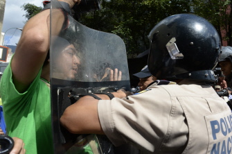 Un simpatizante del gobierno de Nicolás Maduro forcejea con un policía ante la Asamblea Nacional, hoy en Caracas