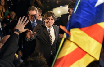 El nuevo presidente del gobierno catalán, Carles Puigdemont (d) saluda a sus simpatizantes al abandonar el parlamento regional, este domingo