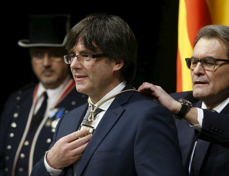 El nuevo presidente catalán Carles Puigdemont recibe una medalla del presidente saliente Artur Mas durante la ceremonia de juramento en el Palacio de 