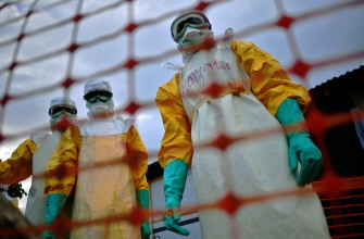 Personal de Médicos sin Fronteras (MSF), con trajes especiales para protegerse del ébola en el cuerpo de una víctima, en Kailahun, Sierra Leona