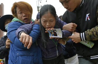 Una mujer sostiene una foto de su hijo después de que el cadáver de un estudiante fuera recuperado en el edificio Dragón Dorado de Tainan
