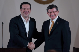 El primer ministro turco Ahmet Davutoglu (d) y su par griego, Alexis Tsipras (i), se dan la mano tras su encuentro de hoy en Esmirna