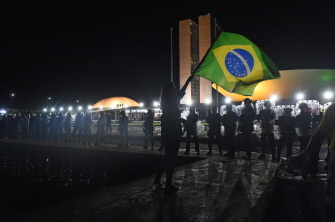 Una mujer ondea una bandera brasileña ante una fila de policías antidisturbios durante la manifestación esta noche ante el Congreso, en Brasilia