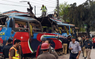 Voluntarios y fuerzas de seguridad inspeccionan el autobús tras la explosión