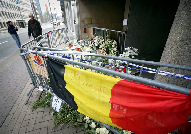 Un hombre camina junto a la entrada de la estación de metro de Maalbeek, escenario de un atentado, decorada con ramos de flores, en Bruselas 