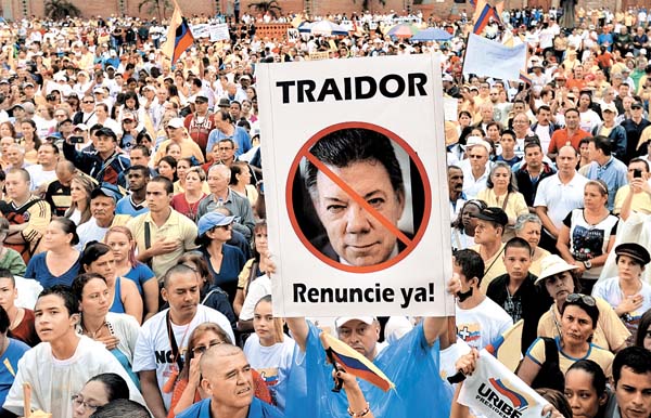 Manifestantes de la ciudad de Cali portan un cartel con la imagen tachada del presidente Juan Manuel Santos.
