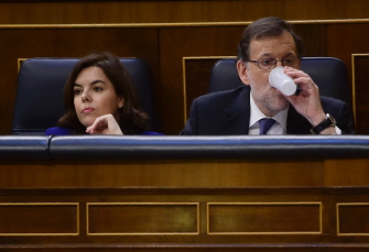 Mariano Rajoy (d) bebe en su escaño de las Cortes mientras la vicepresidenta, Soraya Sáenz de Santamaría, escucha una intervención