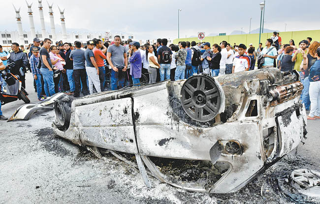 Habitantes de Chalco junto a uno de los vehículos incendiados durante el intento de linchamiento a dos supuestos ladrones. 