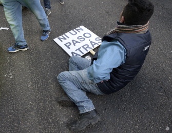 Un participante en la manifestación de los sindicatos en Buenos Aires, sentado en el suelo con una pancarta