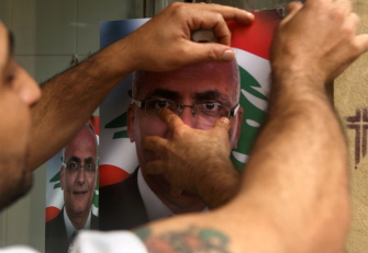 Un libanés fija un cartel de un candidato en las elecciones municipales en la ventana de una tienda en el barrio cristiano de Ashrafiyeh
