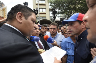 Henrique Capriles (d) entrega un documento en reclamo del referendo revocatorio a un miembro del CNE, el pasado miércoles en Caracas
