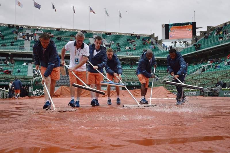 Trabajadores barren el agua, tratando de mantener la cancha en perfectas condiciones