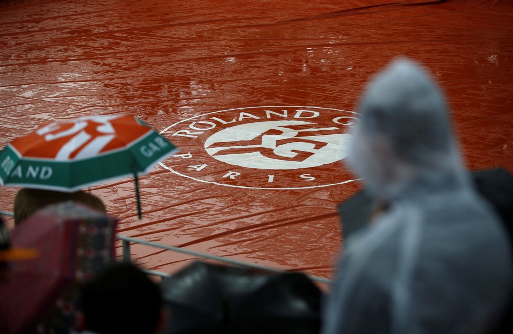 Los espectadores esperan en la cancha protegida por la lluvia el comienzo del segundo día del Abierto de Francia en el Roland Garros  