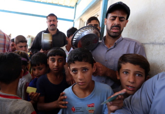 Niños iraquíes, desplazados por los combates en el área de Faluya, esperan su comida en el campo de Alexanzan, en el sur de Bagdad