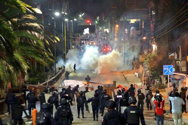 Los policías antimotines se abrieron paso lanzando gas lacrimógeno para dispersar a los manifestantes que trataron de prender fuego a varios vehículos