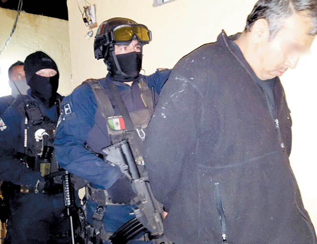 Agentes someten a uno de los capturados durante el operativo. 