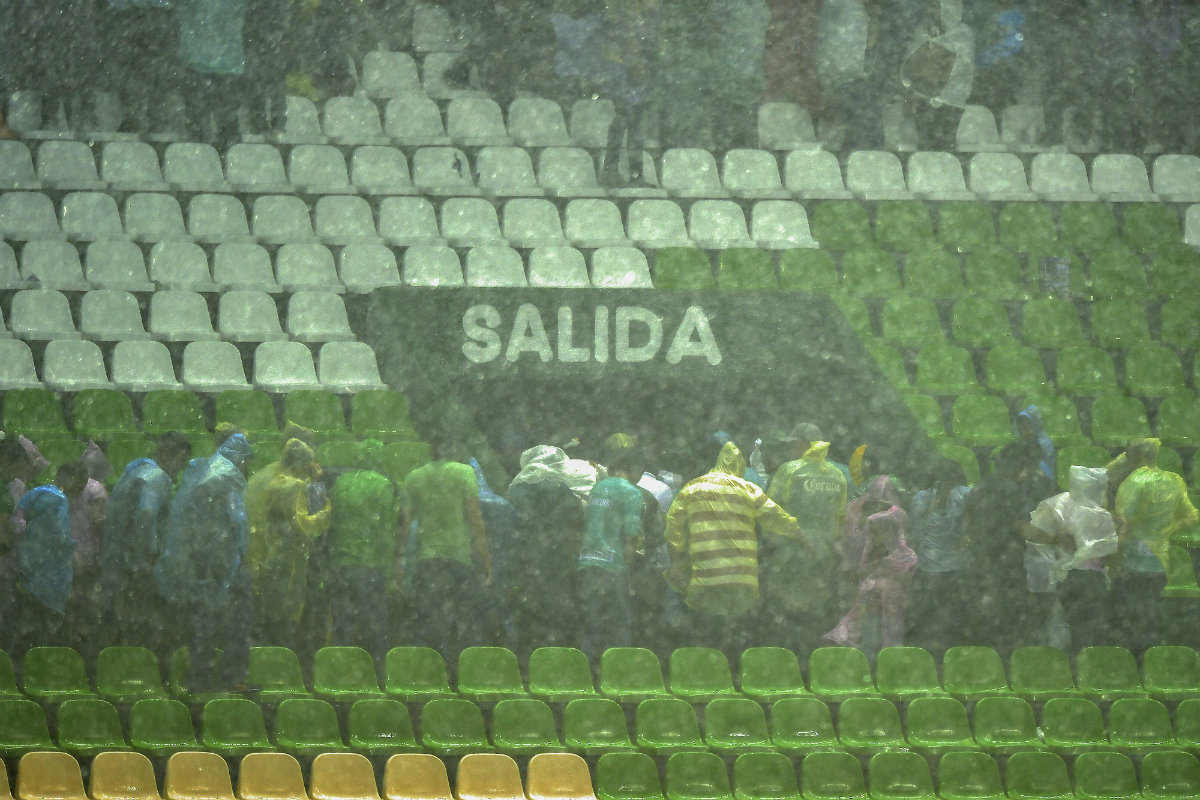 Aficionados tratan de resguadarse de la lluvia en el Estadio León