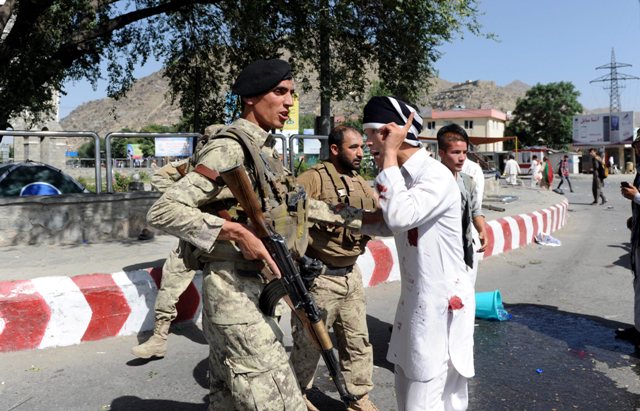 Uno de los asistentes a la manifestación habla con un policía después del atentado en Kabul, donde murieron 61 personas.
