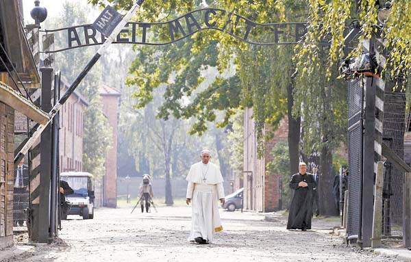 Jorge Mario Bergoglio camina hacia la entrada del antiguo campo de concetración nazi en Polonia.