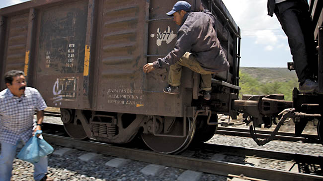 Un hombre intenta ayudar a otro a subir al tren de carga. 