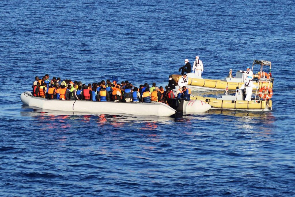 Miembros del ejército italiano ayudan a decenas de inmigrantes durante una operación de rescate en el mar Mediterráneo.