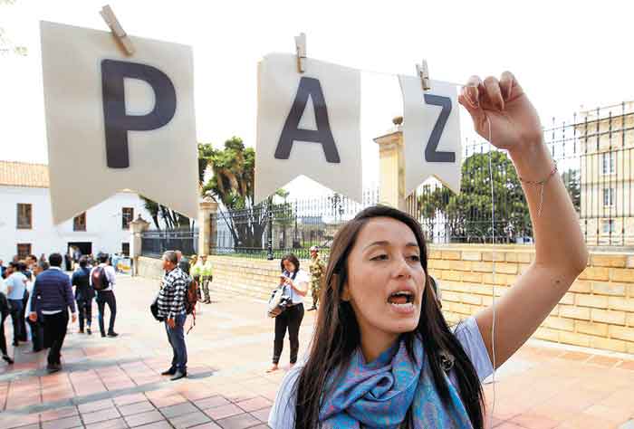 Una manifestante pro negociación grita afuera del lugar donde se reunió el presidente con Uribe.