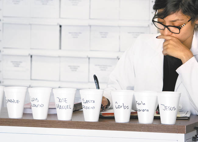 Una doctora prepara las dosis para los pacientes, cuyos nombres están escritos en los vasos. 