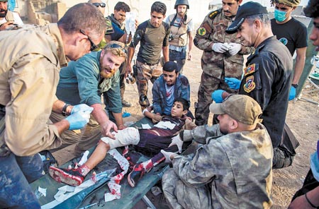 Médicos voluntarios extranjeros tratan a un joven herido en combates en el barrio Samah de Mosul.