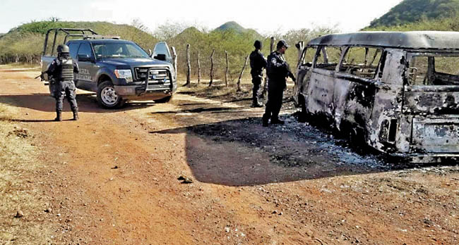 Policías revisan una camioneta calcinada, en la que se presume que viajaban las personas plagiadas. 