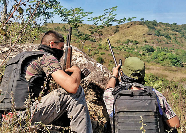 Dos civiles con armas largas se ocultan tras un montículo en espera de repeler cualquier ataque. 
