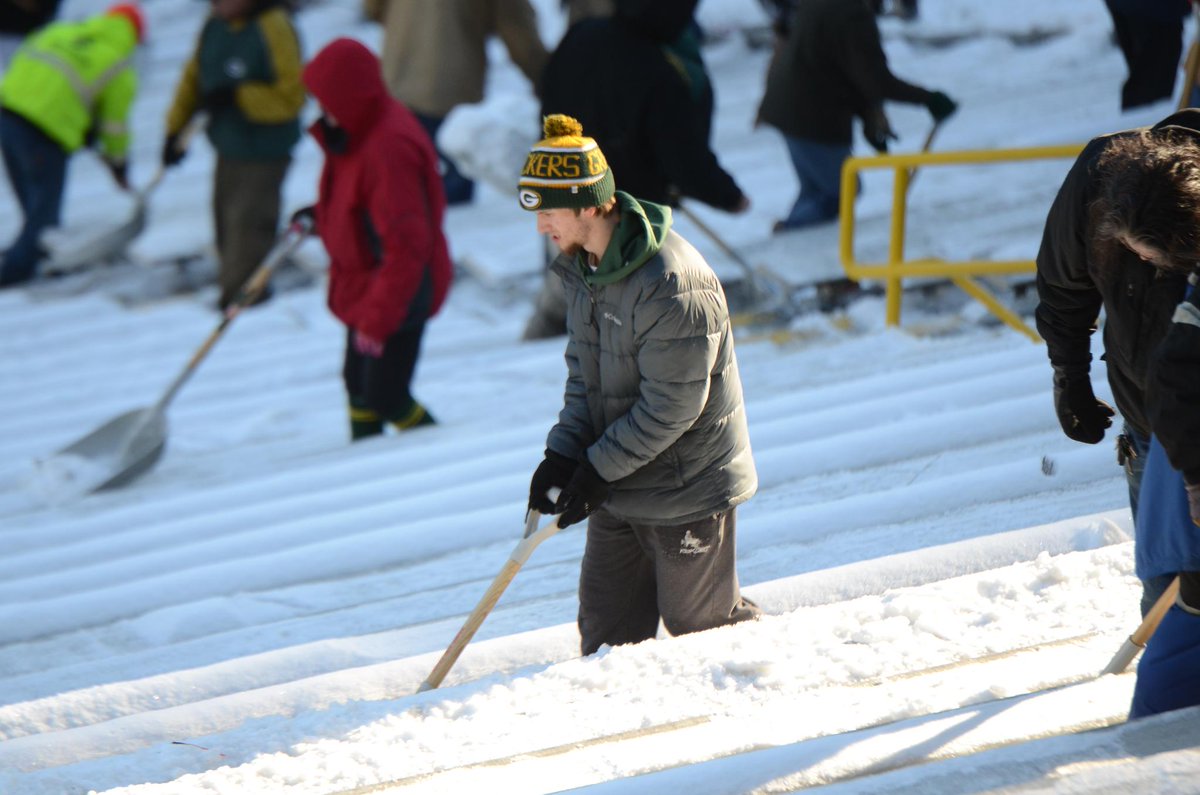 Afición de empacadores remueven la nieve de las gradas del Lambeau Field 