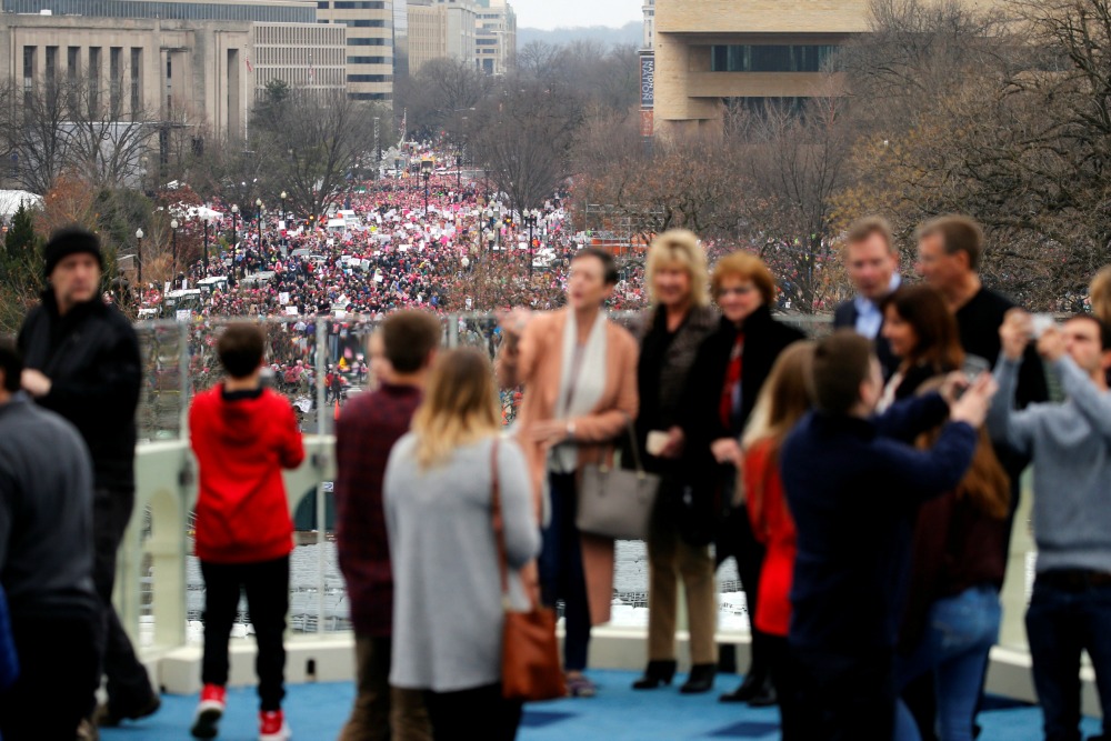 Miembros del Congreso posan en el sitio donde Trump tomó juramento, mientras detrás la gente abarrota las calles
