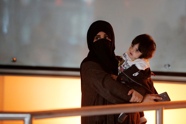 Una mujer en Qatar espera para abordar con su hija un vuelo hacia Estados Unidos.