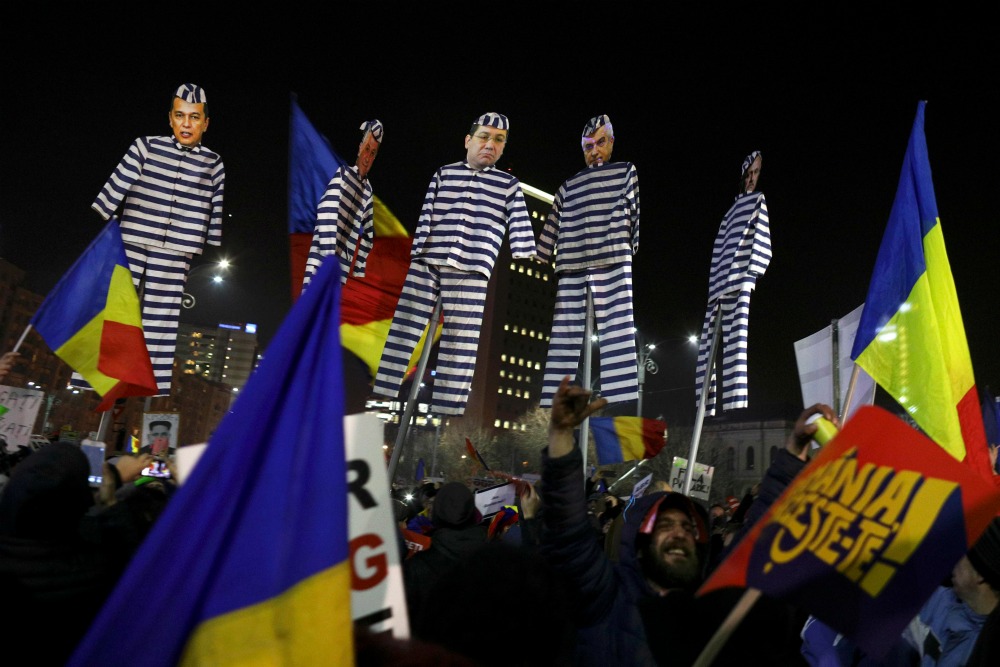 Manifestantes sostienen figuras de funcionarios vestidos como prisioneros durante una manifestación en Bucarest.  
