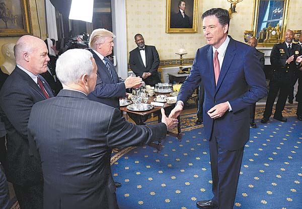 James Comey (d) saluda al vicepresidente Mike Pence en una recepción en la Casa Blanca el 22 de enero.