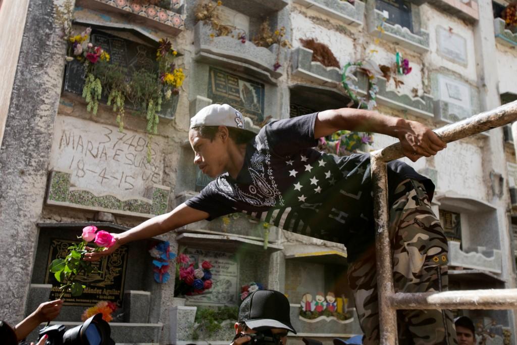 Una trabajadora recibe un par de rosas para la tumba de Madelyn Patricia Hernández Hernández, de 14 años, una niña que murió en el incendio.