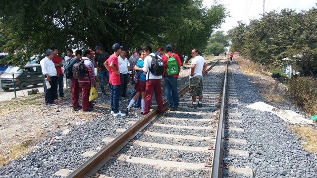 Estudiante platican en crucero del ferrocarril.