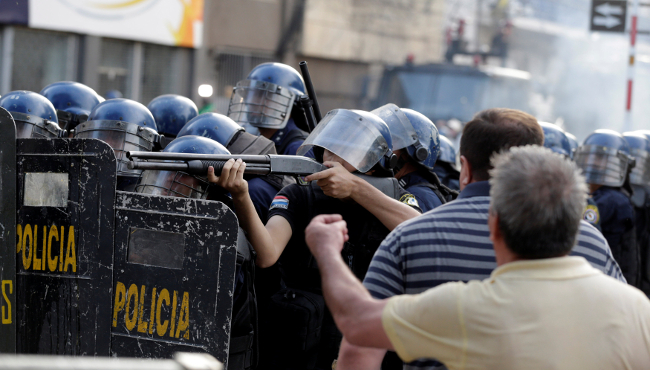 Un policía apunta un arma durante una manifestación contra frente al edificio del Congreso en Asunción.