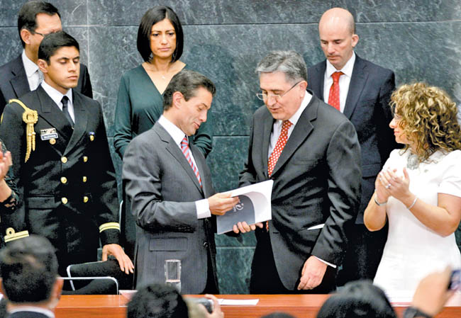 El Presidente ojea el documento que le entregó el "ombudsman" nacional durante su informe de actividades. 
